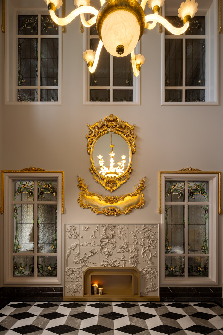 Gilded oval mirror above a carved fireplace
