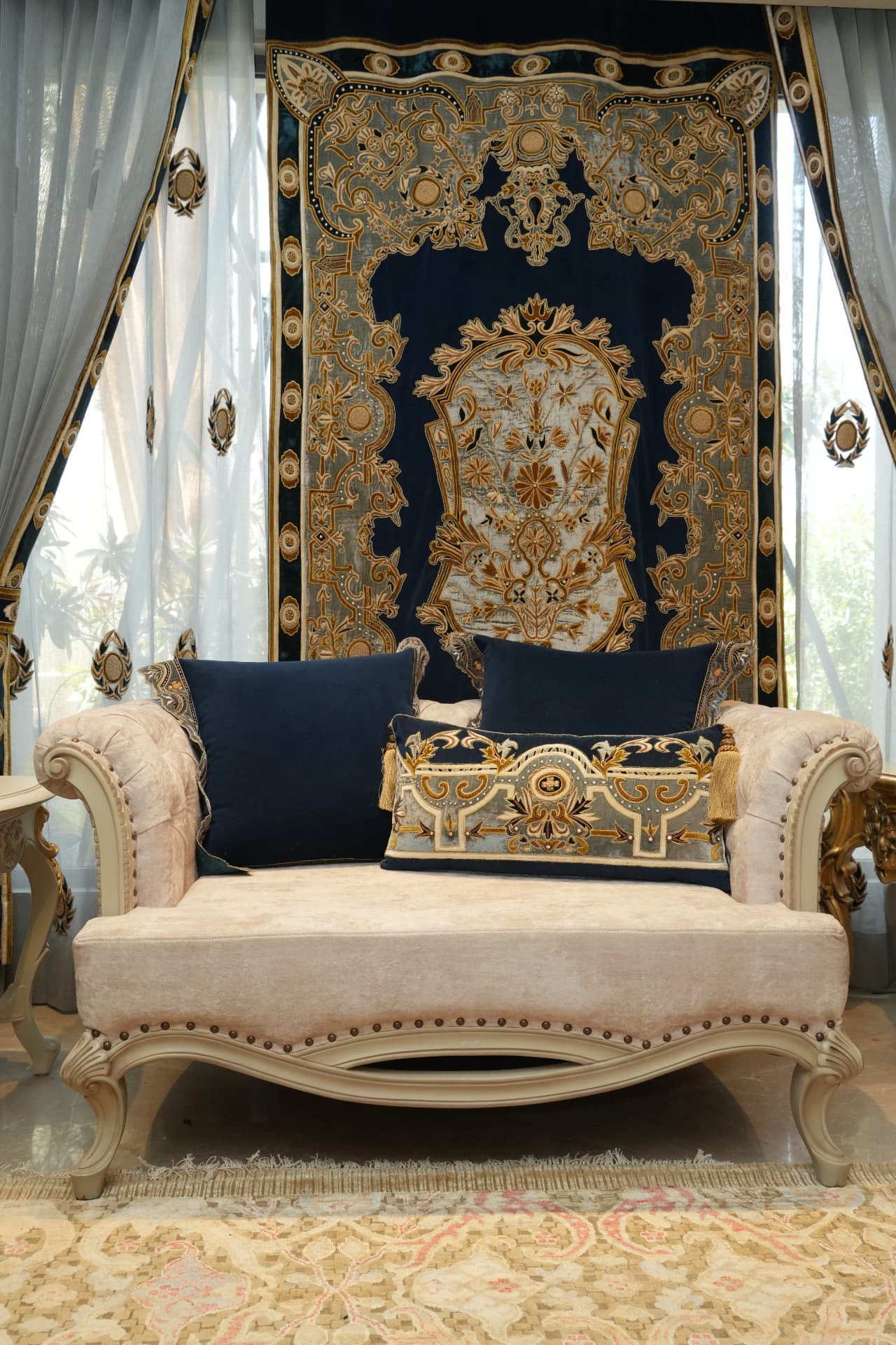 Hand-embroidered navy and gold tapestry above a carved daybed